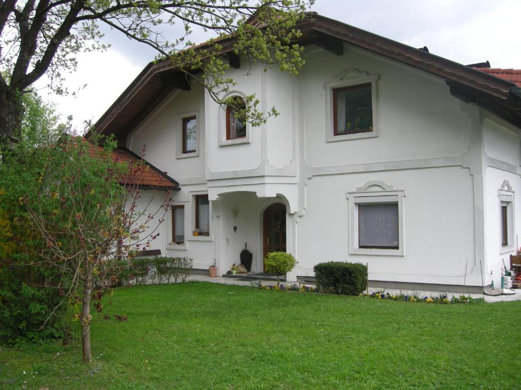 une maison blanche avec une pelouse verte devant elle dans l'établissement Ferienwohnung Anna, à Sankt Kanzian