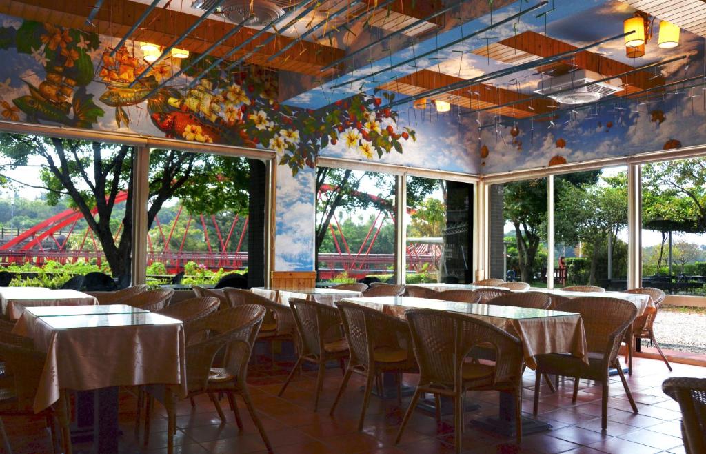 a dining room with tables and chairs and windows at Rainbow Bridge B&amp;B in Sanzhi