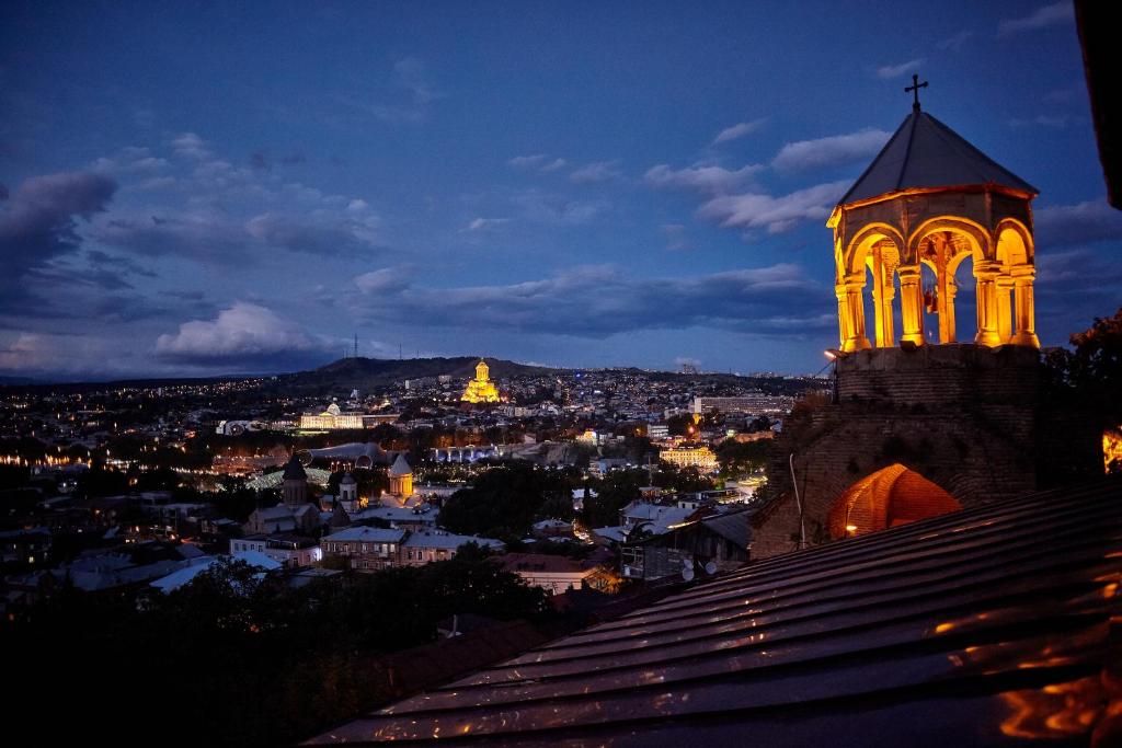 - Vistas a la ciudad por la noche con una torre del reloj en Bethlehem Terrace, en Tiflis