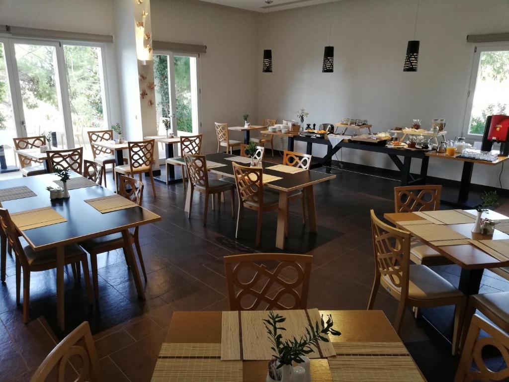 um restaurante com mesas e cadeiras de madeira e janelas em Orizontes View Hotel em Katakolon