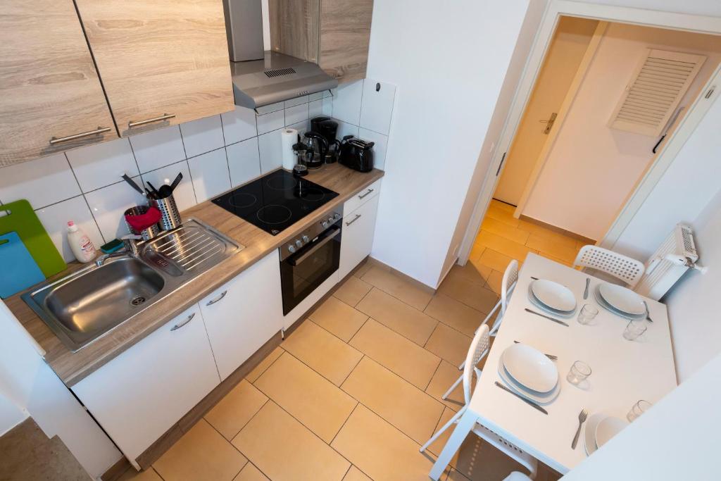 een kleine keuken met een wastafel en een tafel bij AVR Apartment HOF 8 in Bremerhaven