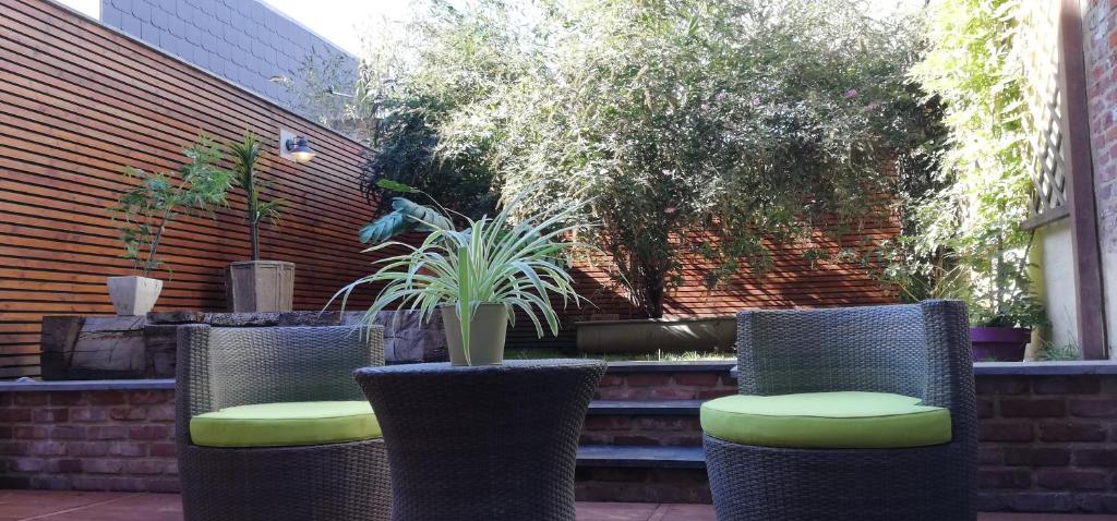 un patio avec trois chaises et des plantes dans l'établissement maison familiale près de bruxelles et paridaisia, à Enghien