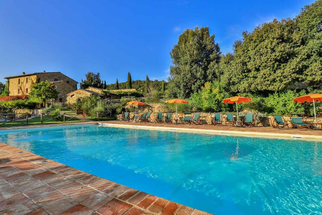 a large swimming pool with chairs and umbrellas at Le Mascie in Sovicille