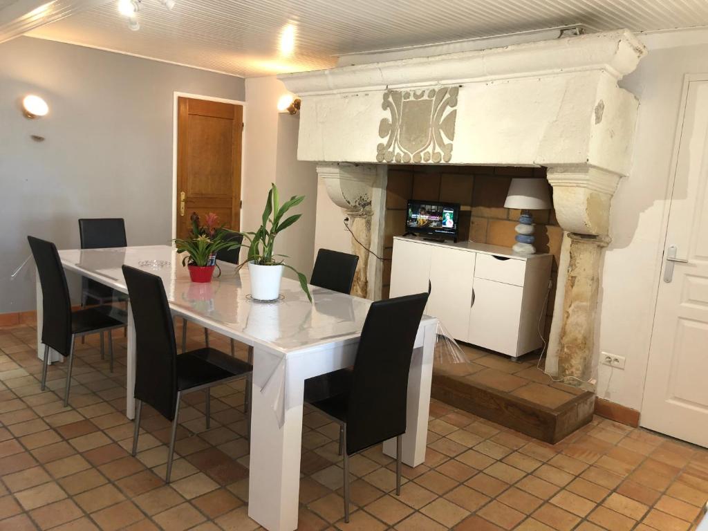 a dining room with a white table and black chairs at LES GITES DE MONTMARTRE in Le Perrier