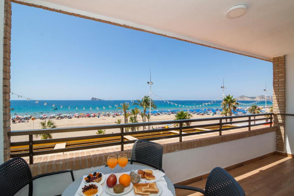 a table with food on a balcony with a view of the beach at Les Dunes Comodoro in Benidorm