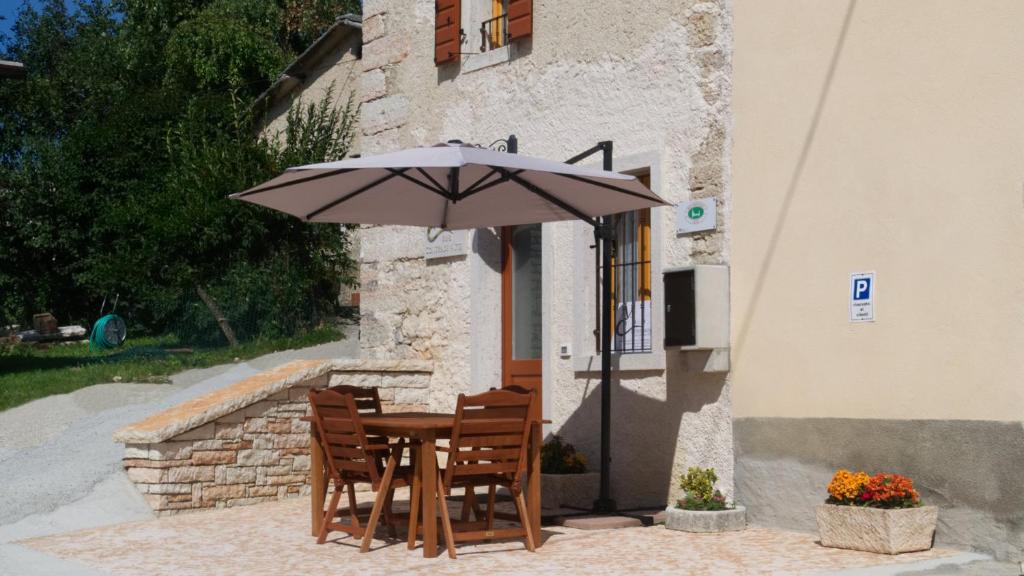 einen Tisch und Stühle mit einem Regenschirm vor einem Gebäude in der Unterkunft B&B Contrade Alte in SantʼAnna dʼAlfaedo