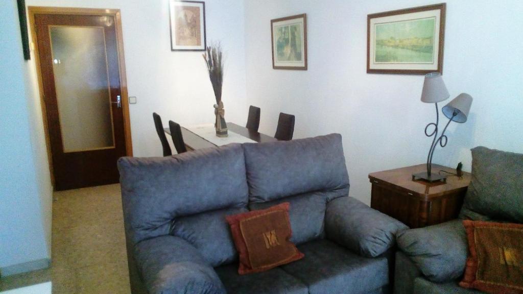 a living room with a blue couch and a table at VIVIENDA COMPLETA EN SEVILLA in Seville