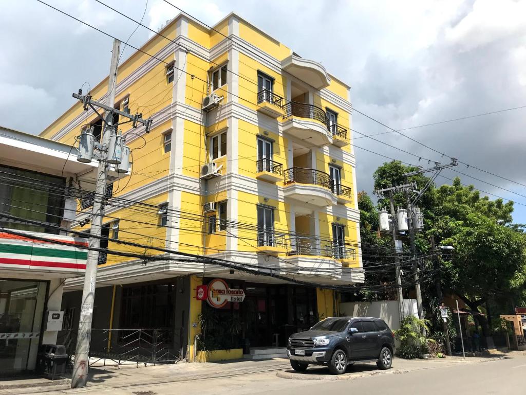 a yellow building with a car parked in front of it at Casa Rosario Hotel in Cebu City