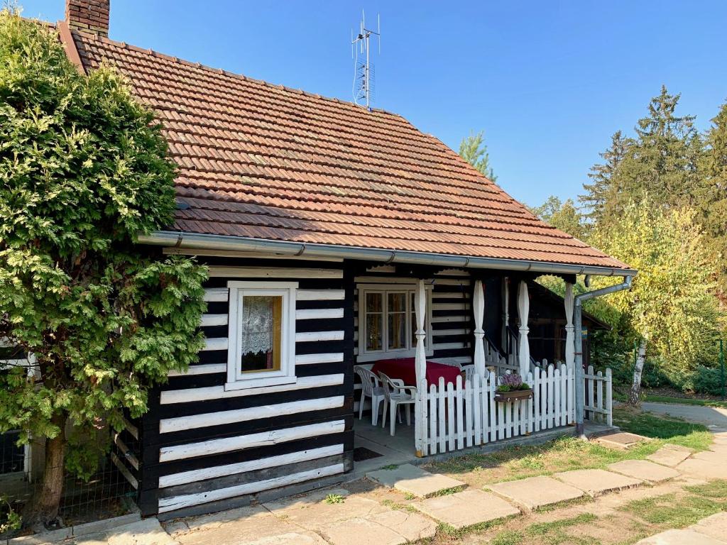 mały czarno-biały dom z białym płotem w obiekcie Chaloupka v Českém Ráji w mieście Blata