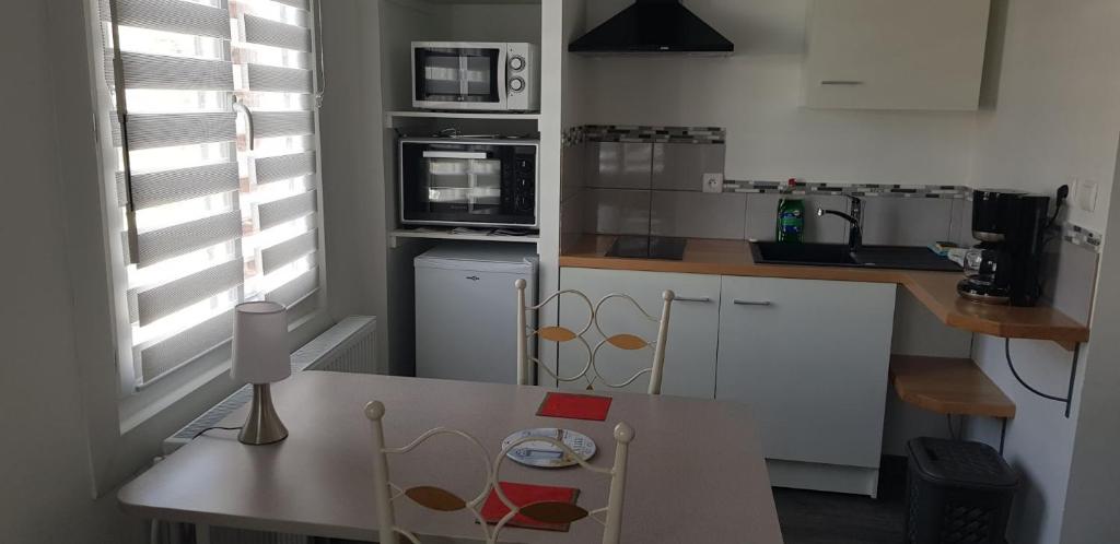 a kitchen with white cabinets and a table with a chair at Val&#39; Appart 1 in Valenciennes