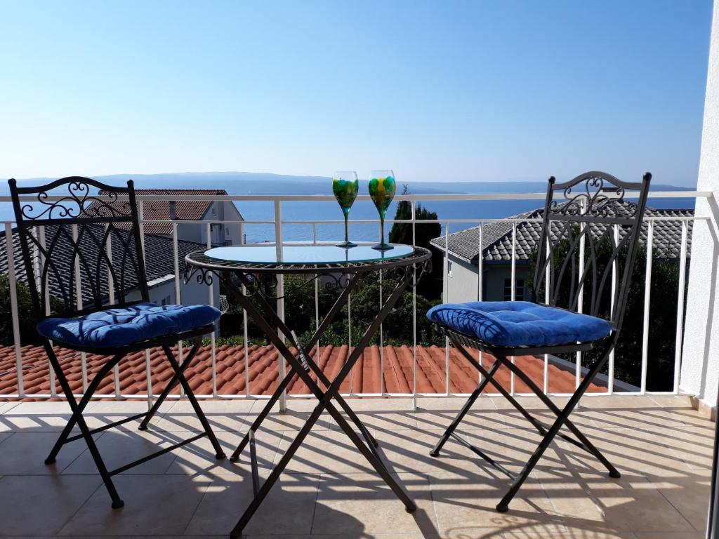 two chairs and a table with two glasses on a balcony at Appartement Suncano in Crikvenica