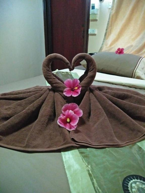 a bed with a dress with two pink flowers at Phi Phi Green Hill Resort in Phi Phi Don
