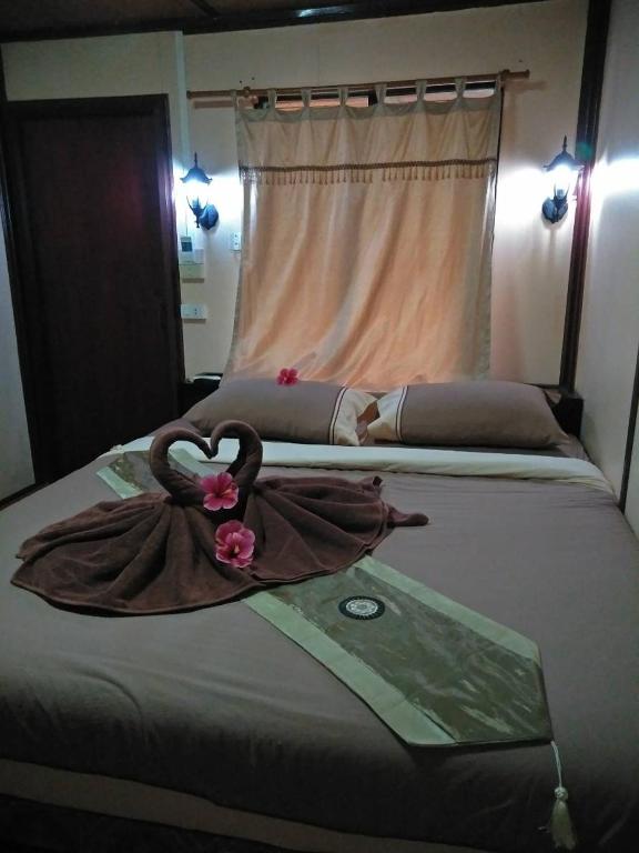 a bed with a robe and flowers on it at Phi Phi Green Hill Resort in Phi Phi Don