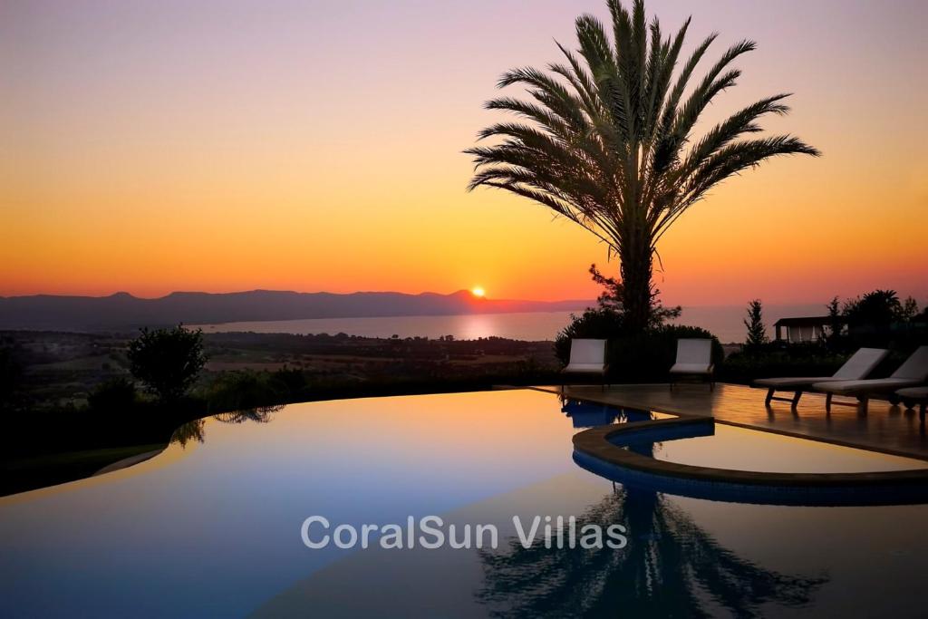 una palmera y una piscina con la puesta de sol en el fondo en ELITE Amazing Villa, by Coral Sun Villas, en Polis Chrysochous