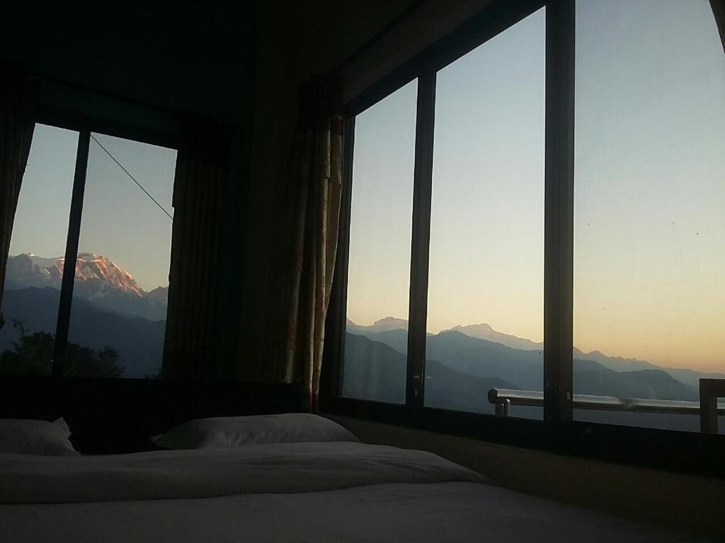 a bedroom with windows with a view of mountains at Himalayan crown lodge in Pokhara