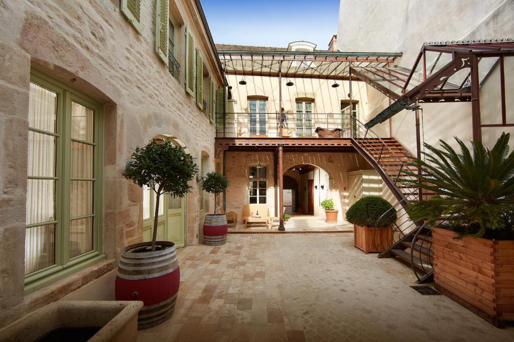 a courtyard of a building with a staircase and plants at Le Clos Sainte-Marguerite in Beaune