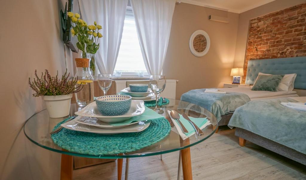 een woonkamer met een glazen tafel met borden erop bij Happy Day Apartments in Opole