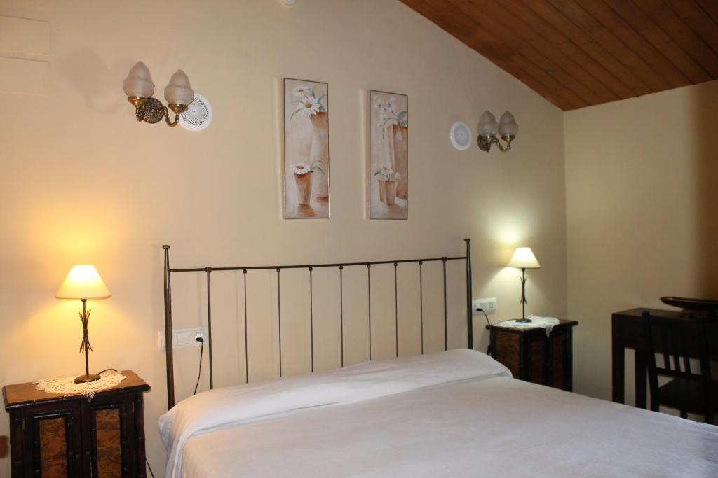 1 dormitorio con 1 cama con 2 lámparas y 2 cuadros en la pared en La Bodega Del Camino aka Albergue On TheLe en Lorca