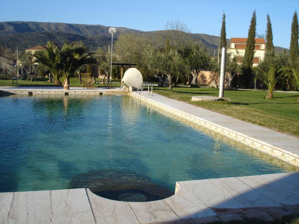 a swimming pool in a park with trees and mountains at Posada Tresmentiras in Aldeanueva del Camino