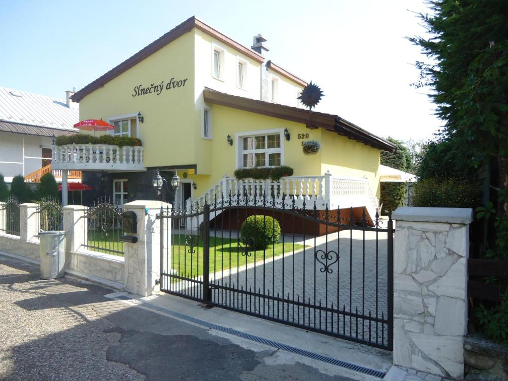 a black fence in front of a yellow house at Slnecny Dvor in Veľká Lomnica