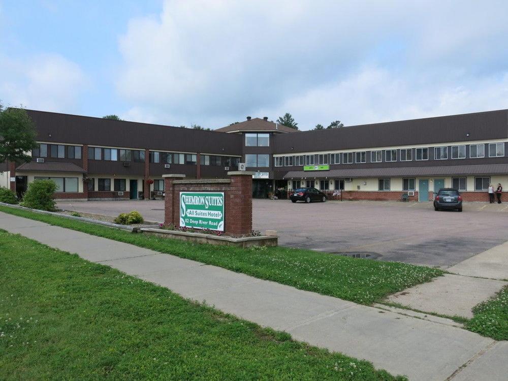 a building with a sign in front of a parking lot at Shemron Suites Hotel in Deep River