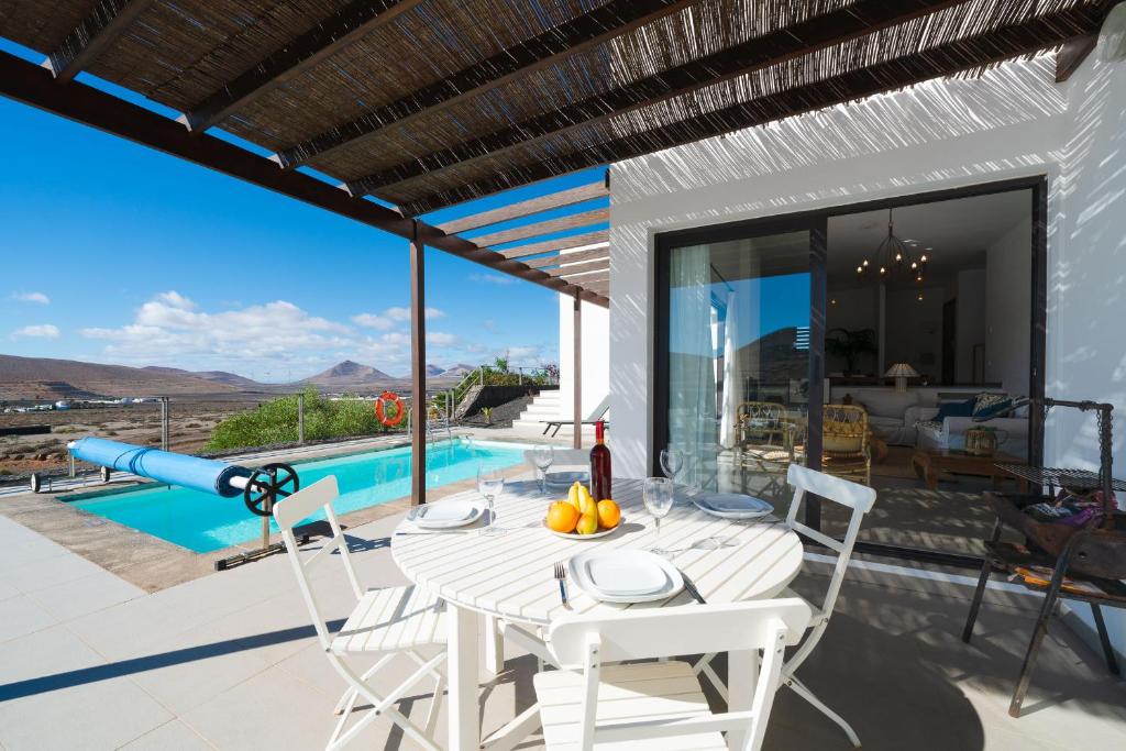 una mesa blanca y sillas en un patio con piscina en El Tucan, excelentes vistas y privacidad, en Nazaret