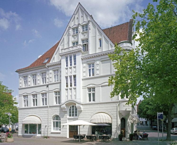 ein großes weißes Gebäude mit Tischen davor in der Unterkunft Hotel & Café KleinerGrünauer in Bad Salzuflen