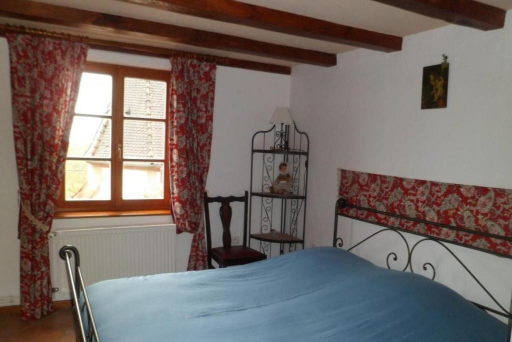 ein Schlafzimmer mit einem blauen Bett und einem Fenster in der Unterkunft Gîte L'Instant Durable in Oberbronn