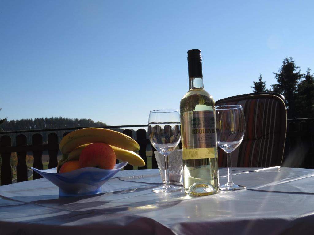 梅德巴赫的住宿－Ferienwohnung Krämershagen，桌子上放有水果的一瓶葡萄酒和玻璃杯