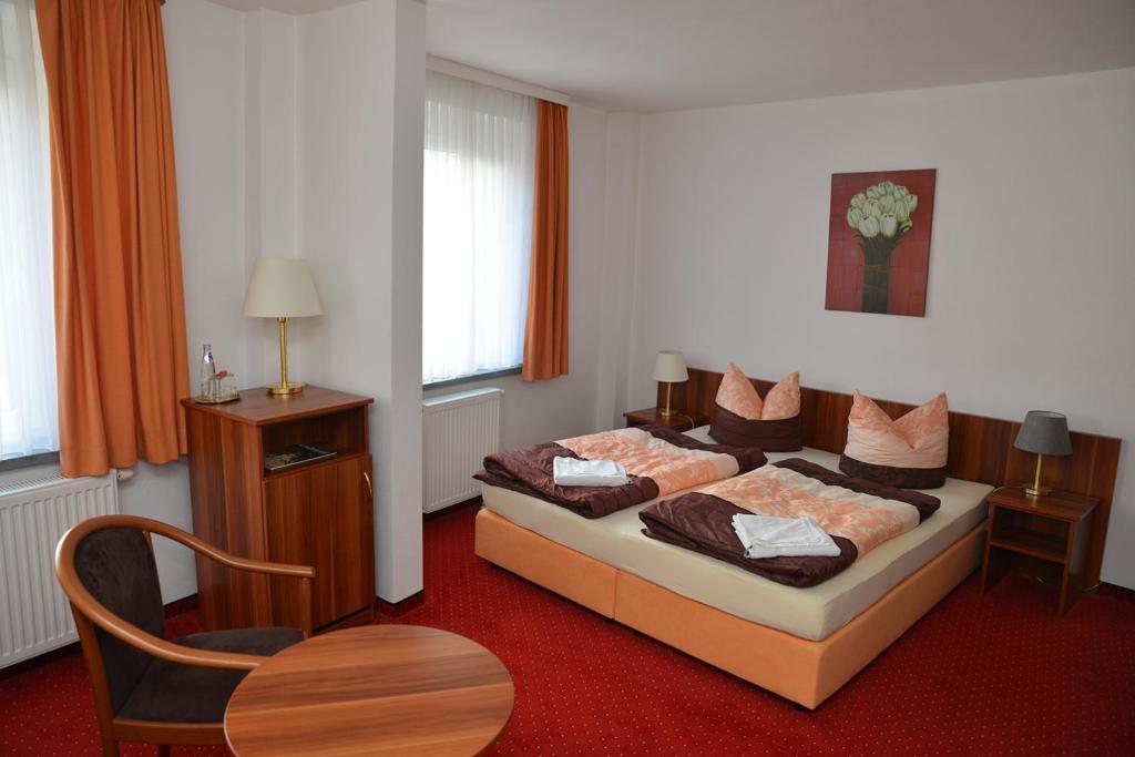 a bedroom with a bed and a table and a chair at Haus Sankt Florian in Halberstadt