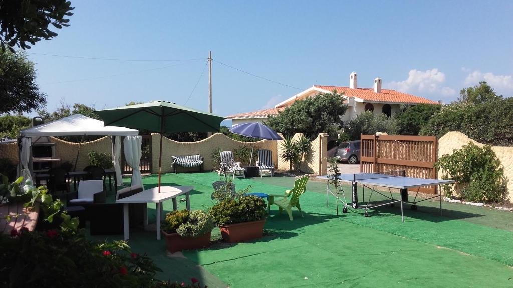 a patio with tables and umbrellas in a yard at Apartment The Sea of Sardinia in Putzu Idu