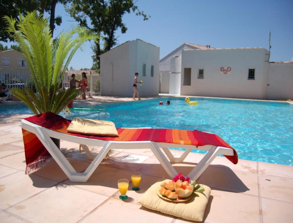 una piscina con una mesa con bebidas y un bol de fruta en Vacancéole - Les Bastides de Fayence, en Tourrettes
