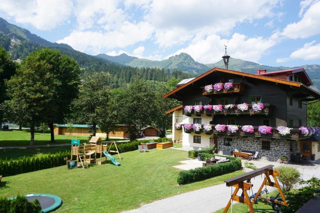 une maison avec des fleurs sur son côté dans l'établissement KENDLGUT Appartements am BioBauernhof inklusive unbegrenztem Eintritt in die Alpentherme, à Bad Hofgastein