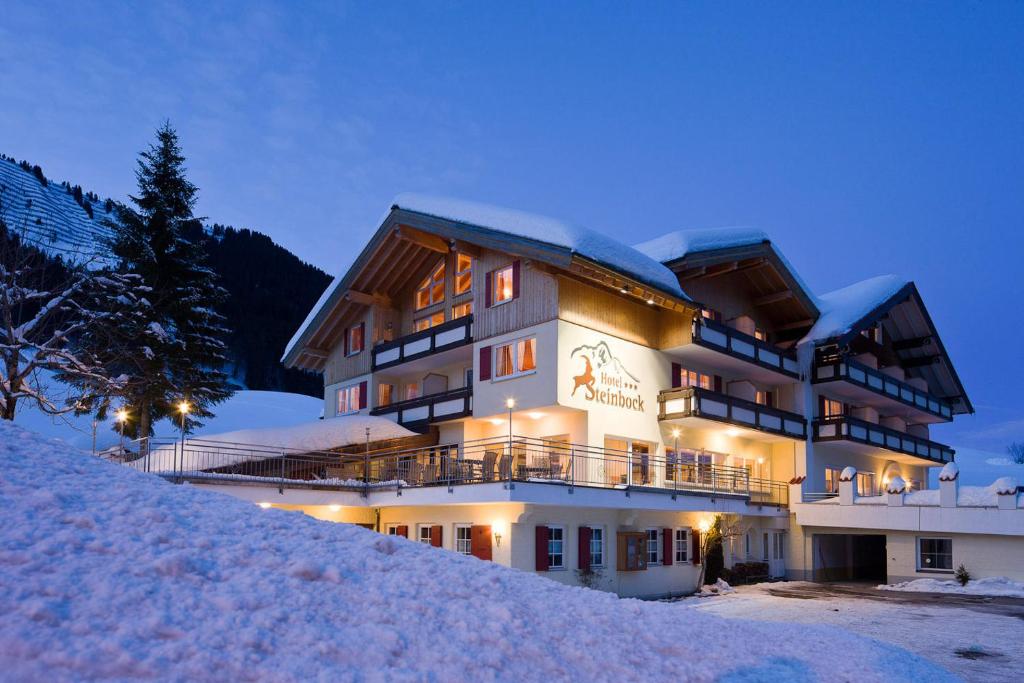 ein großes Gebäude auf einem schneebedeckten Hang in der Unterkunft Hotel Steinbock in Mittelberg