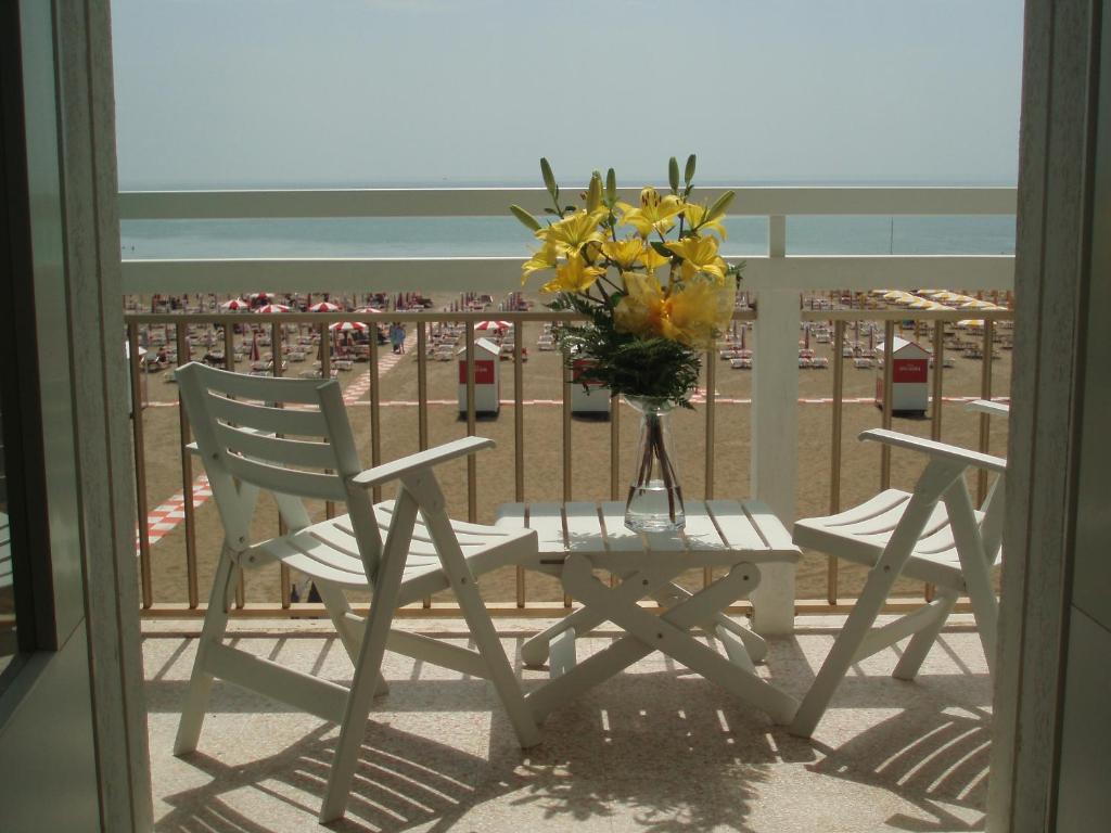 una mesa y sillas con un jarrón de flores en el balcón en Hotel Tizian Beach, en Caorle