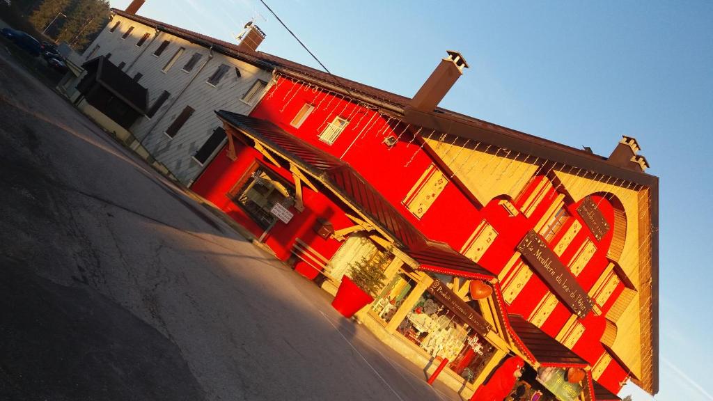 un bâtiment rouge et jaune avec un magasin dans l'établissement Grand Studio rénové, tout confort, belles prestations - Résidence du Bois de l'Ours, aux Rousses