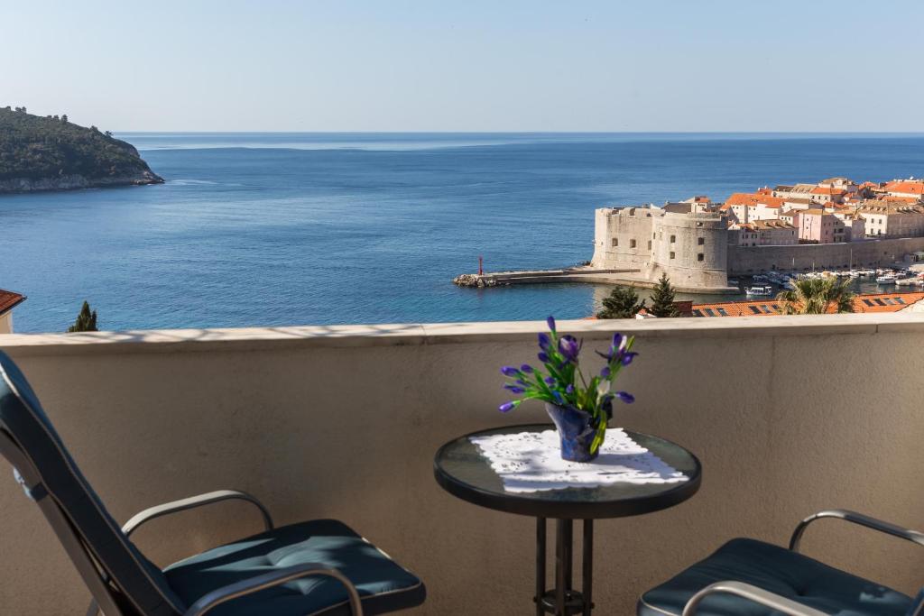 uma mesa e cadeiras numa varanda com vista para o oceano em Apartments Dalmatin em Dubrovnik