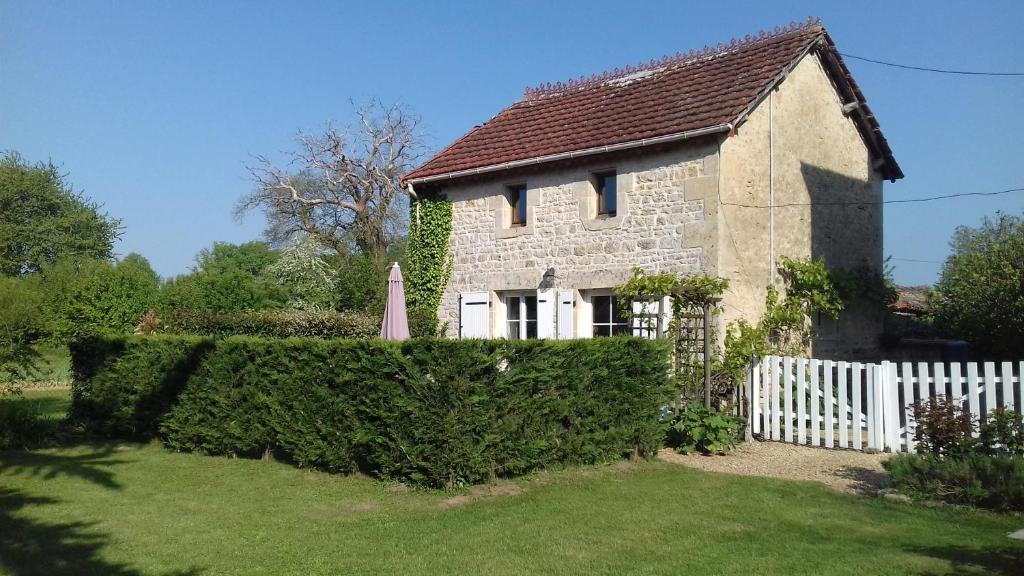 an old stone house with a white fence at Les Roses Trémières in Lezay
