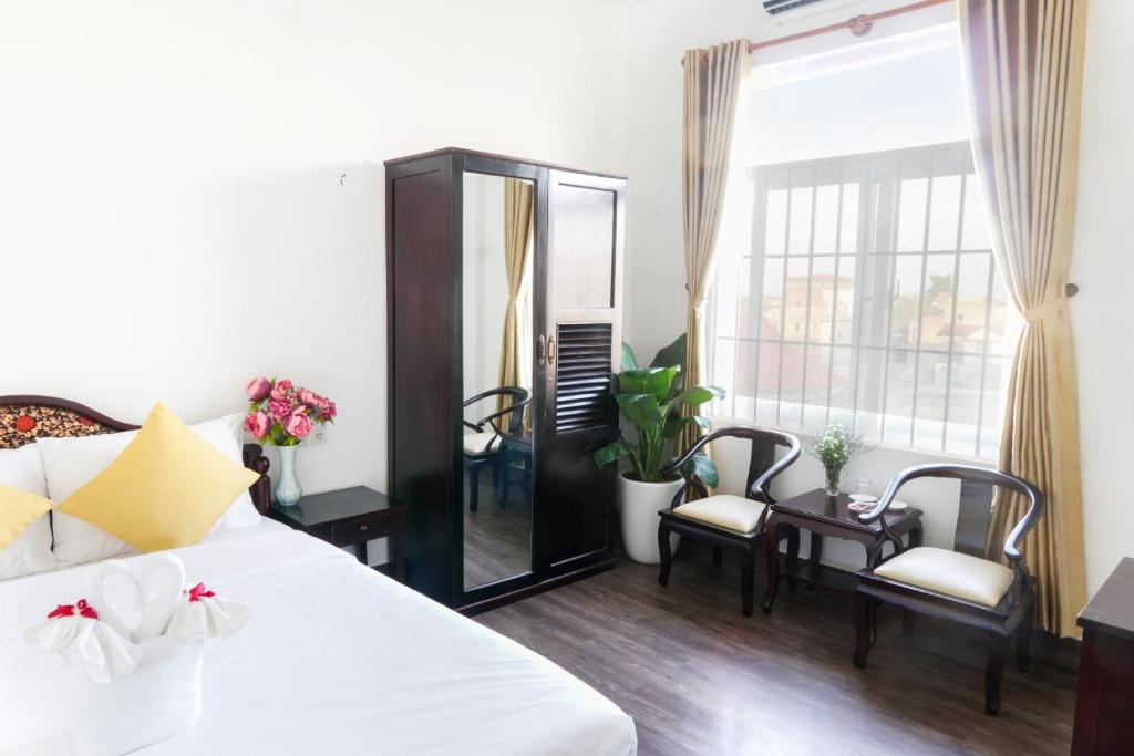 um quarto com uma cama branca e um espelho em Hue Royal Hotel em Hue