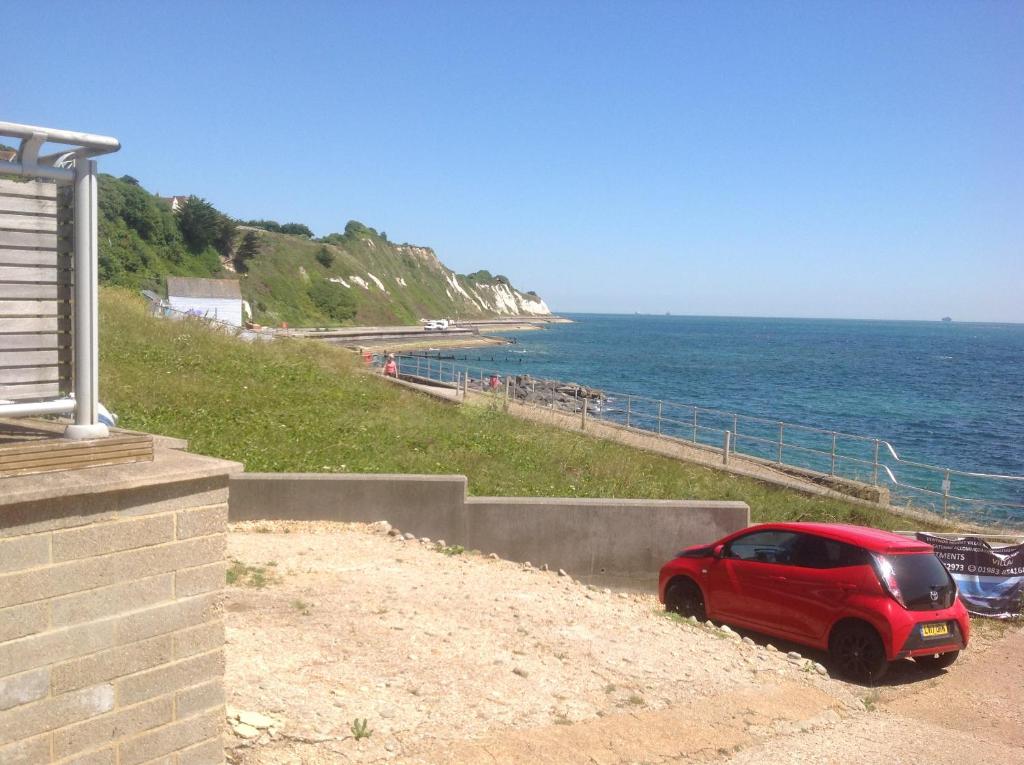 a red car parked on the side of a beach at Angels Corner, Ventnor Bay in Ventnor
