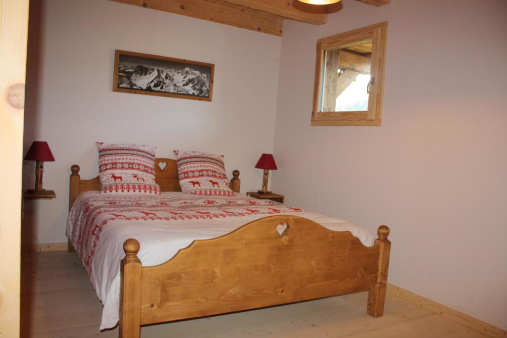 um quarto com uma cama de madeira e almofadas vermelhas em La Case em Abondance