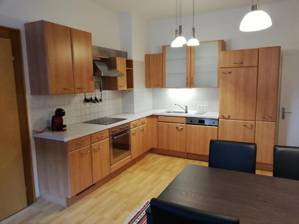 Apartment zur Schmiede في غوربمينغ: مطبخ بدولاب خشبي وطاولة مع كراسي