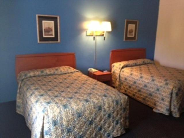 Budget Inn - Madison في Madison: سريرين في غرفة فندق بجدران زرقاء