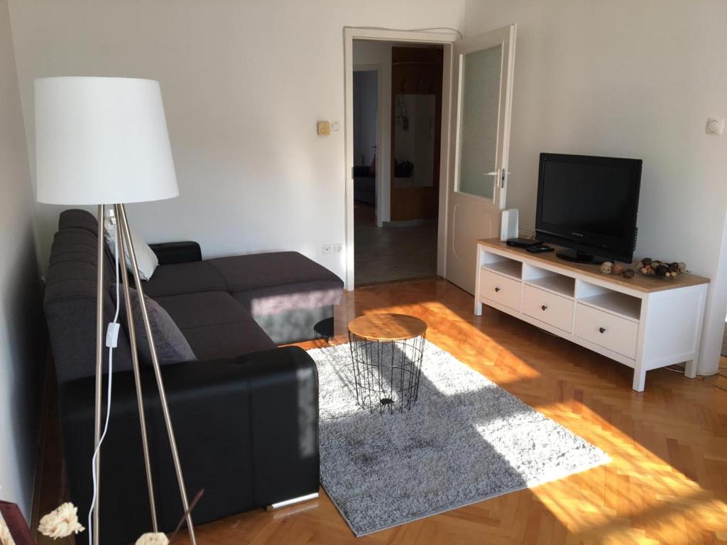 uma sala de estar com um sofá preto e uma televisão em Gold em Sopron