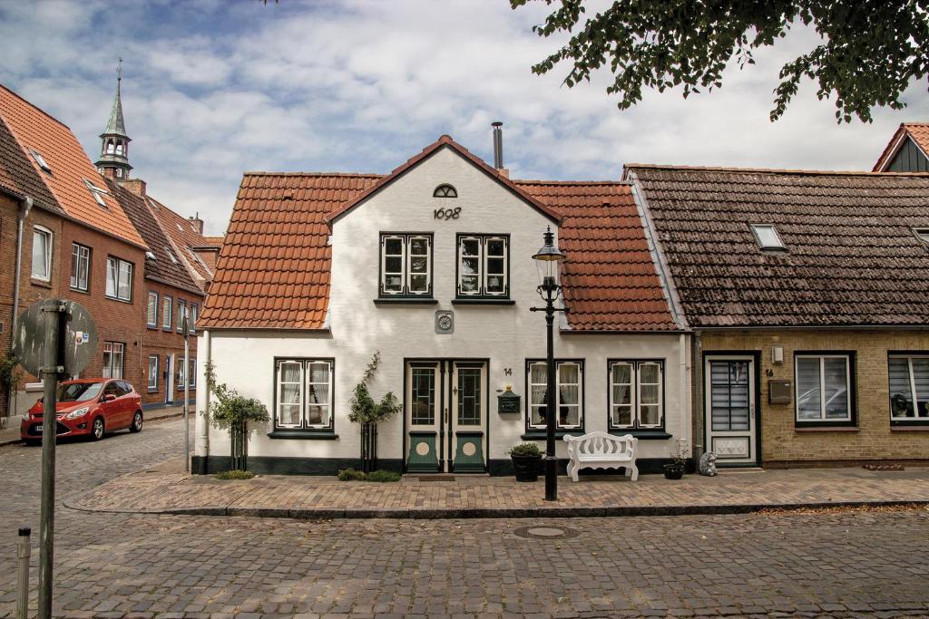 a white building with red roofs on a street at Friesenhaus in Friedrichstadt