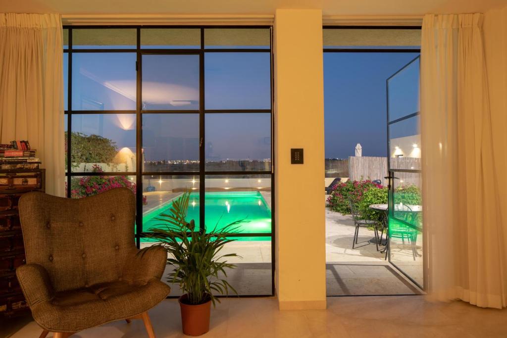 a living room with a view of a pool seen through sliding glass doors at DesertB in Giv'ot Bar