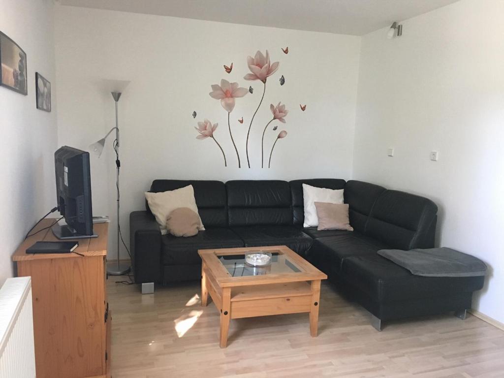 ein Wohnzimmer mit einem schwarzen Sofa und einem Couchtisch in der Unterkunft Ferienwohnungsvermietung Leitel in Brandenburg an der Havel