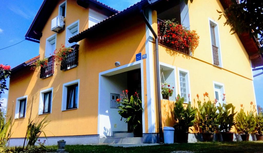una casa amarilla con flores a un lado. en Apartment Medeni, en Rakovica