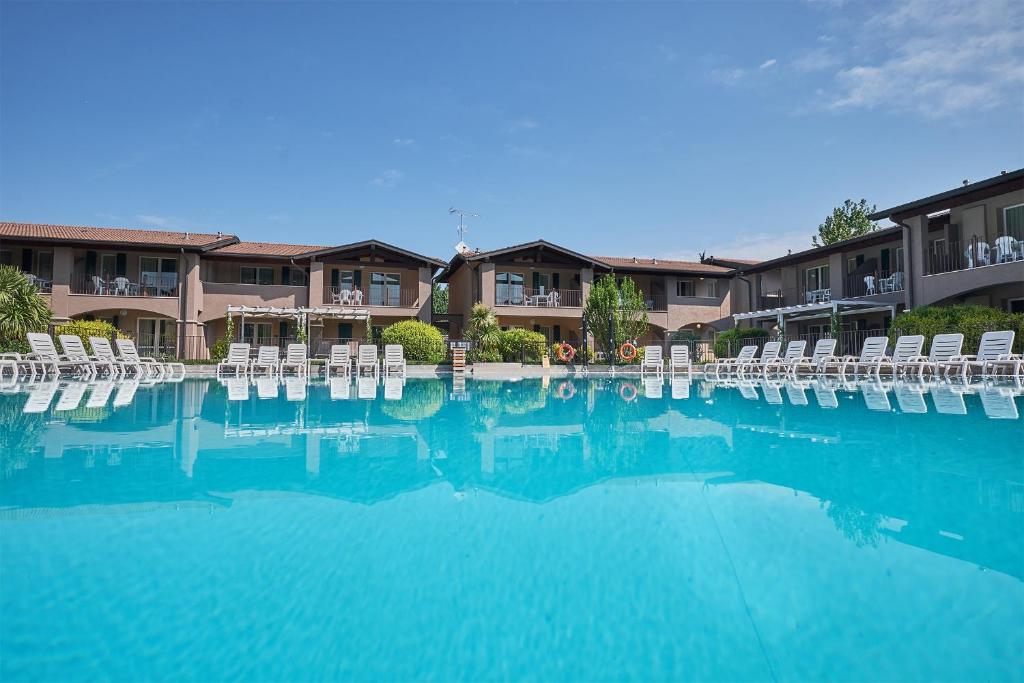 a large swimming pool with chairs and blue water at Villaggio Turistico Lugana Marina in Sirmione