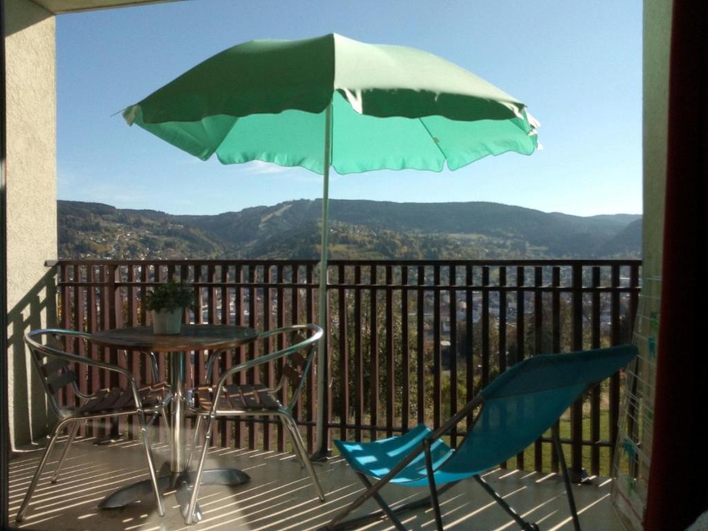 une table et des chaises sur un balcon avec un parasol dans l'établissement Studio les bleuets, à Gérardmer